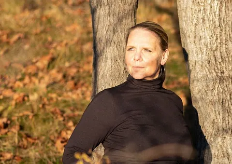 Kvinne lener seg mot tre